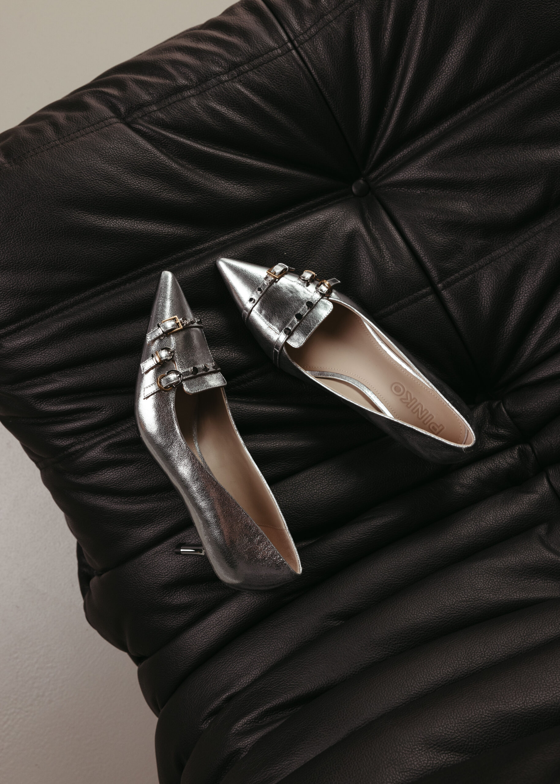 Silver pointed shoes on black couch